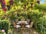 Idyllischer Gartensitzplatz unter Weinreben